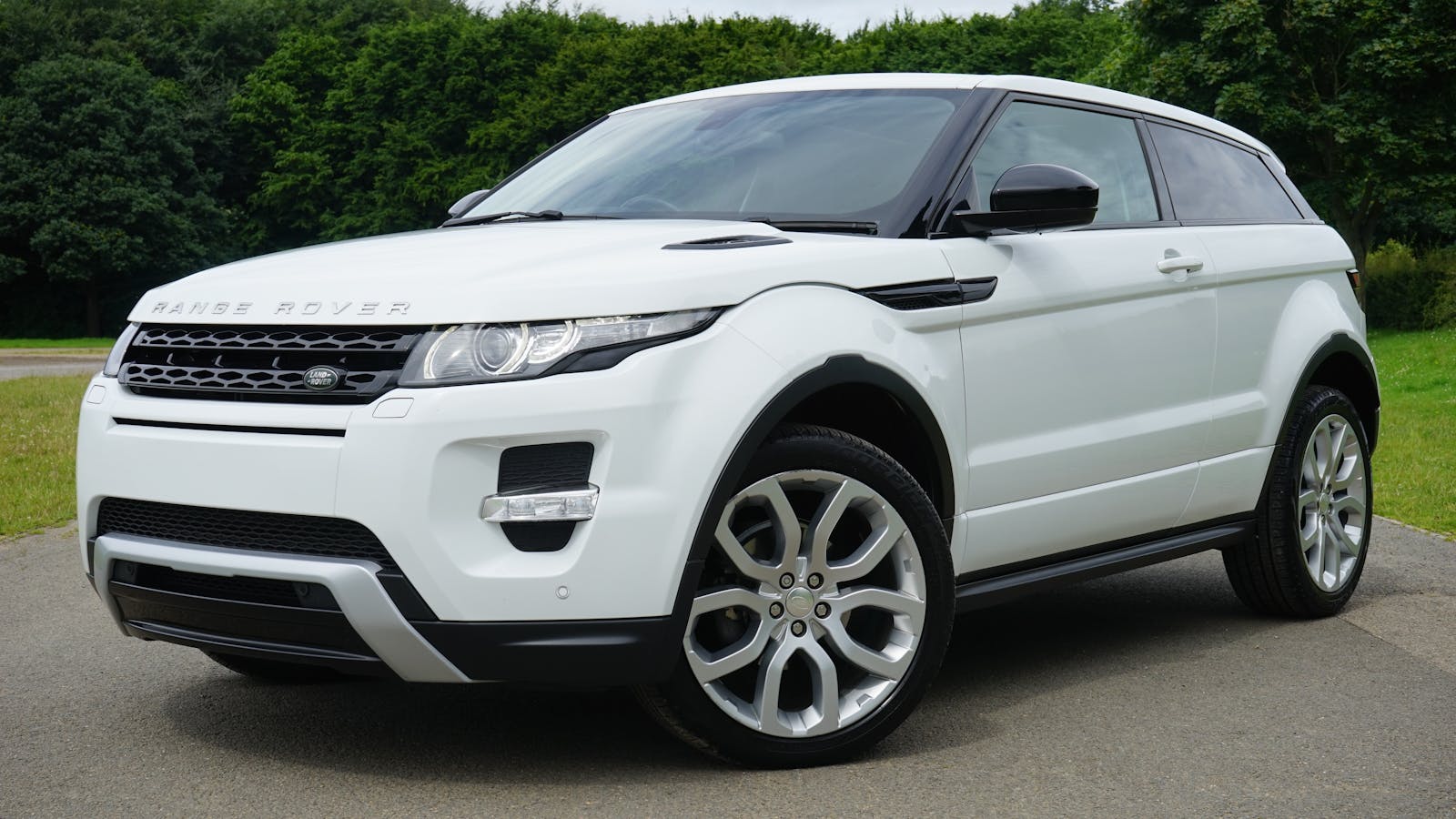 auto Stylish white Range Rover parked on a road in a green outdoor setting, showcasing its luxury design.